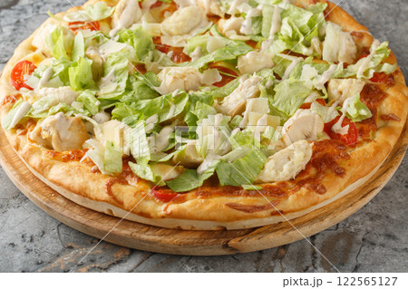 Caesar style pizza with chicken, lettuce, tomatoes, cheese and Caesar dressing closeup on the wooden board. Horizontal Caesar style pizza with chicken, lettuce, tomatoes, cheese and Caesar dressing closeup on the wooden board. Horizontal 122565127