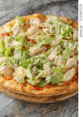 Delicious pizza Caesar salad with chicken, parmesan,, cherry tomatoes and fresh lettuce closeup on the wooden board. Vertical 122565129