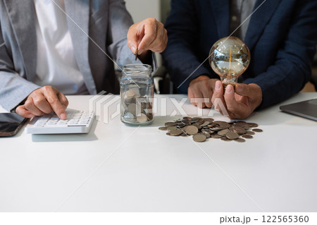 businessman hand holding lightbulb with saving money in office. businessman hand holding lightbulb with saving money in office. 122565360