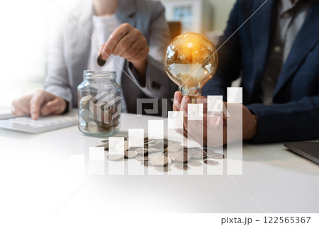 businessman hand holding lightbulb with using laptop computer and money stack in office. idea saving energy and accounting finance concept in office. businessman hand holding lightbulb with using laptop computer and money stack in office. idea saving energy and accounting finance concept in office. 122565367