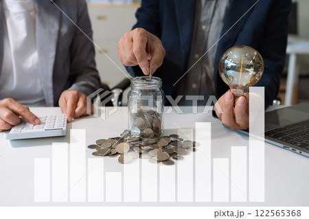 businessman hand holding lightbulb with using laptop computer and money stack in office. idea saving energy and accounting finance concept in office. businessman hand holding lightbulb with using laptop computer and money stack in office. idea saving energy and accounting finance concept in office. 122565368