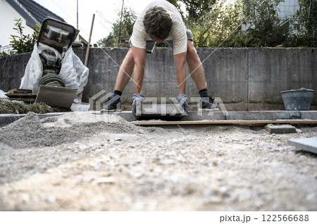 Worker laying concrete paver 122566688