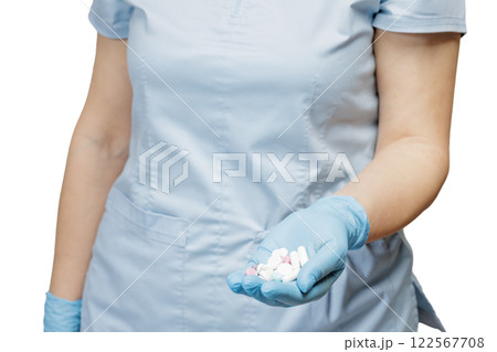 Hand of a female doctor in a blue glove with pile of pills. 122567708