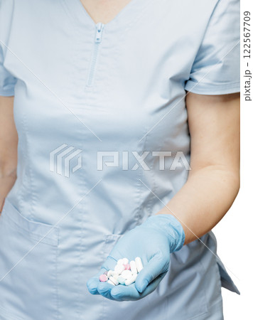 Hand of a female doctor in a blue glove with pile of pills. Hand of a female doctor in a blue glove with pile of pills. 122567709