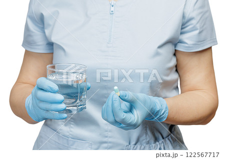 Hands of a female doctor with a glass of water and a capsule. 122567717