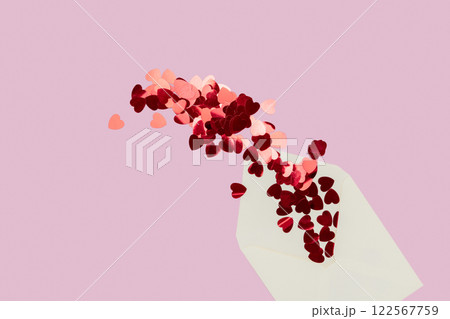 Creative minimalist composition of cream letter envelope spilling heart-shaped confetti, set against a pink background, symbolizing love and warmth. Creative minimalist composition of cream letter envelope spilling heart-shaped confetti, set against a pink background, symbolizing love and warmth. 122567759