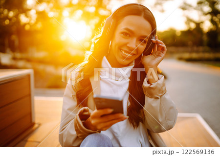 Young woman listens to music, audiobook or podcast. Communication in social networks. Lifestyle. 122569136