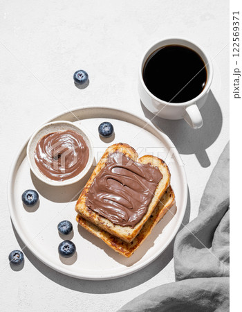 Toasted bread with chocolate cream on a plate on a light background Toasted bread with chocolate cream on a plate on a light background 122569371