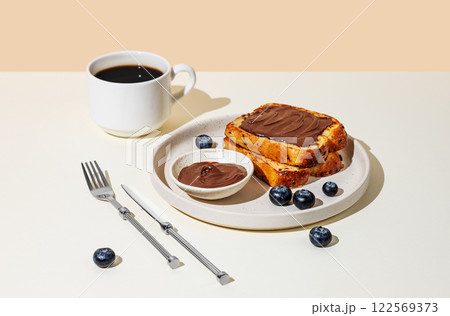 Toasted bread with chocolate cream on a plate with blueberry on a light background Toasted bread with chocolate cream on a plate with blueberry on a light background 122569373