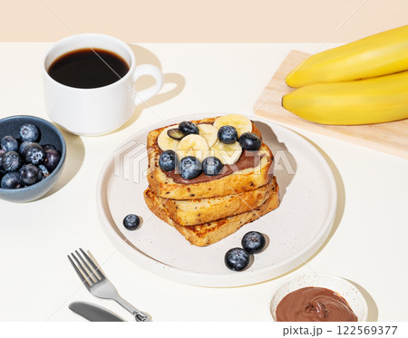 Toasted bread with chocolate cream, blueberries and banana on a plate on a light background 122569377