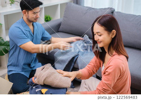 group of friend  sorting and packing clothes into a donation box.community support, and charitable giving 122569483