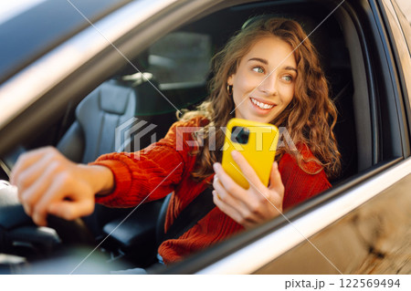 Woman sitting in a car looking into a smartphone, paying for parking and navigating in the city. 122569494