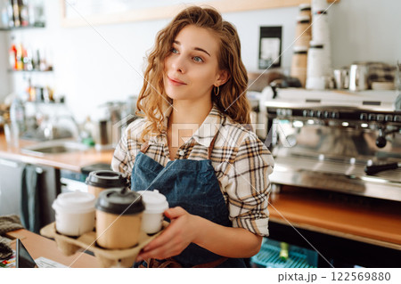 Female barista holding disposable takeaway cups. Business concept. Drinks to go. Female barista holding disposable takeaway cups. Business concept. Drinks to go. 122569880