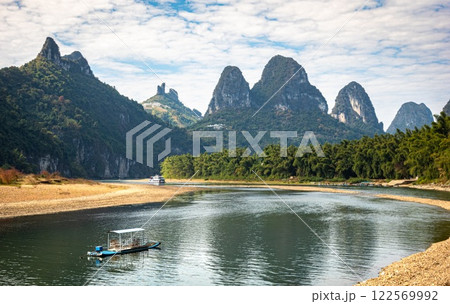 A wooden boat floats on Li river with karst mountains near Guilin, Guanxi, China A wooden boat floats on Li river with karst mountains near Guilin, Guanxi, China 122569992