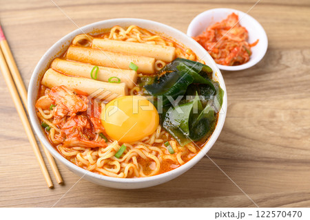 Spicy noodles soup with Tteokbokki, Wakame seaweed and fresh egg yok eating with kimchi cabbage 122570470
