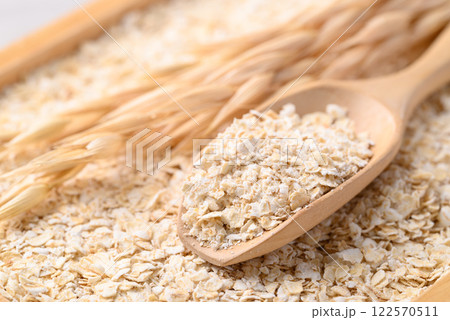 Oat flakes in wooden scoop, Food ingredient in oatmeal, muesli or porridge 122570511