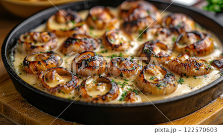 Grilled scallops in creamy garlic sauce garnished with parsley in black skillet Grilled scallops in creamy garlic sauce garnished with parsley in black skillet 122570603