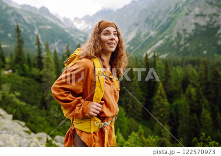 Young traveler woman with a yellow backpack on a cliff. Sports concept, traveler. Active lifestyle. Young traveler woman with a yellow backpack on a cliff. Sports concept, traveler. Active lifestyle. 122570973