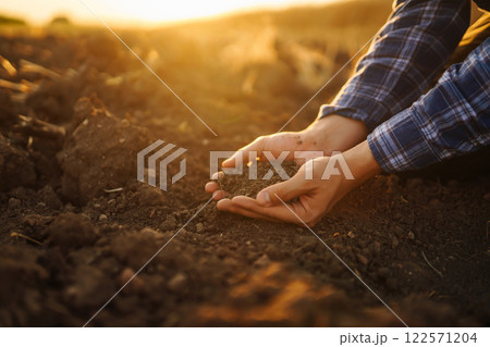 Farm owner checks quality of soil with his hands with tablet and checks fertility before sowing. Farm owner checks quality of soil with his hands with tablet and checks fertility before sowing. 122571204