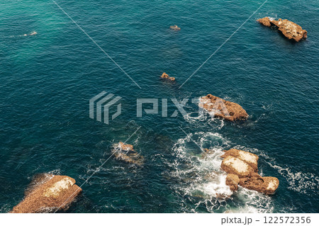 Aerial view of deep blue ocean with scattered rocky formations 122572356