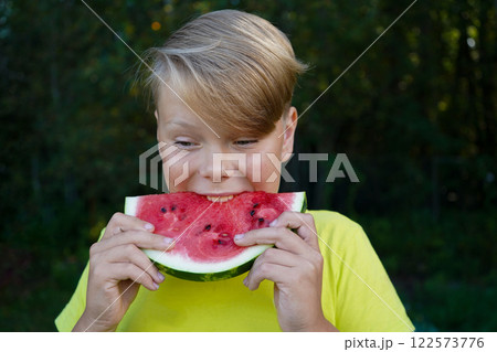 Cheerful boy with a watermelon in a green forest 122573776