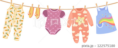 Baby clothes hanging on a clothesline are drying in the sunlight, featuring charming patterns of carrots, hearts, clouds, and a vibrant rainbow, adding a playful touch to any nursery 122575180