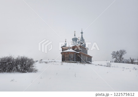 Snowy hill with an old wooden church, Cherdyn. Snowy hill with an old wooden church, Cherdyn. 122575612