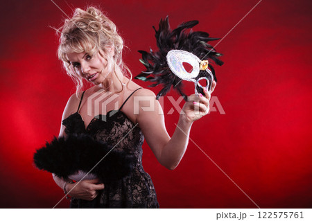 Woman holding carnival mask feather fan in hand Woman holding carnival mask feather fan in hand 122575761
