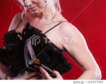 Woman holding carnival mask feather fan in hand Woman holding carnival mask feather fan in hand 122575762