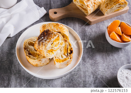 Delicious roll with cottage cheese and tangerine on a plate on the table Delicious roll with cottage cheese and tangerine on a plate on the table 122576153