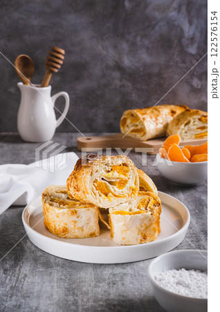 Sweet roll of cottage cheese with tangerine wrapped in lavash on a plate on the table vertical view Sweet roll of cottage cheese with tangerine wrapped in lavash on a plate on the table vertical view 122576154