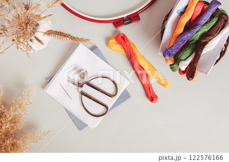 Canvas, embroidery floss, scissors, needle, thimble and cross stitch hoop on table top view 122576166