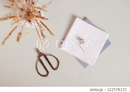 Canvas, needle, thimble and scissors for cross stitching on gray background top view Canvas, needle, thimble and scissors for cross stitching on gray background top view 122576172