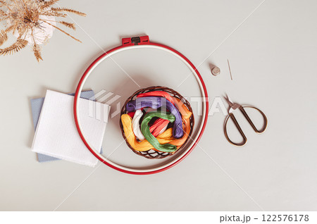 Basket with colored floss, canvas, embroidery hoop and scissors on gray background top view 122576178