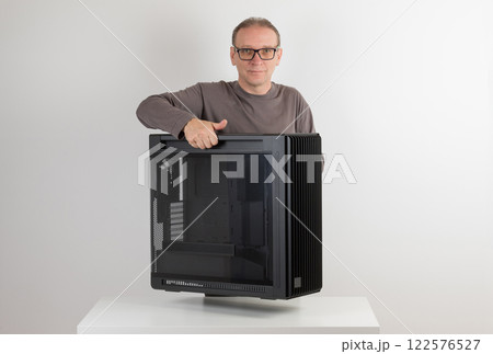 Man holding a heavy PC case, weight 15,8 kg, empty big tower, chassis, on side is tempered-glass. Man holding a heavy PC case, weight 15,8 kg, empty big tower, chassis, on side is tempered-glass. 122576527