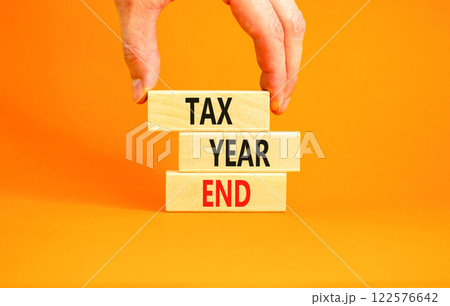 Tax year end symbol. Concept words Tax year end on beautiful wooden blocks. Beautiful orange background. Businessman hand. Business tax year end concept. Copy space. 122576642