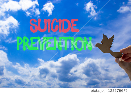 Suicide prevention symbol. Concept words Suicide prevention on beautiful blue sky. Psychologist hand, wooden bird. Beautiful blue sky background. Psychological suicide prevention concept Copy space Suicide prevention symbol. Concept words Suicide prevention on beautiful blue sky. Psychologist hand, wooden bird. Beautiful blue sky background. Psychological suicide prevention concept Copy space 122576673