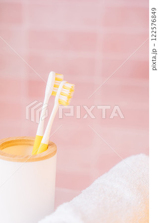 Two yellow toothbrushes in holder in bathroom on pink background Two yellow toothbrushes in holder in bathroom on pink background 122576849