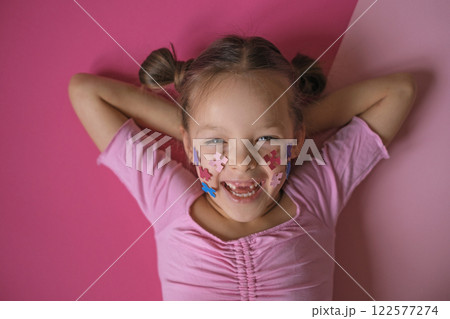 A cheerful laughing child decorated his cheeks with pieces of a colored puzzle, a symbol of autism, as a sign of support for people with this disease. A cheerful laughing child decorated his cheeks with pieces of a colored puzzle, a symbol of autism, as a sign of support for people with this disease. 122577274