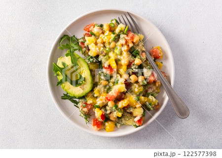 Enjoy a nutritious salad of boiled millet, chickpeas, fresh vegetables, and avocado, topped with olive oil, perfect for a wholesome vegetarian diet rich in vitamins and minerals 122577398