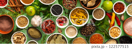 A beautiful collection of colorful spices and herbs, showcasing their natural aromas and vibrant hues on a gentle green background, banner 122577515