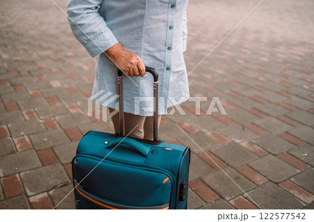 Female traveler walking with a blue suitcase at the modern transport stop outdoors. Concept of an urban transportation and travel 122577542