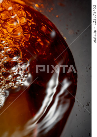 Golden drink is poured into the glass, creating beautiful waves and splashes. 122578452