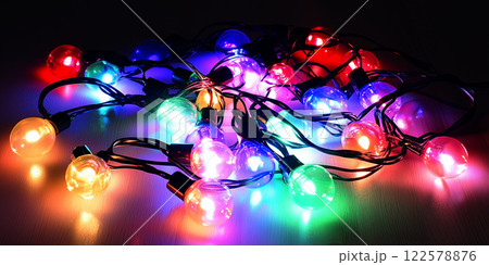 Colorful string lights. Multicolored bulbs glow brightly. Perfect party decoration. Vibrant RGB bulb design, high-angle shot, dark background 122578876