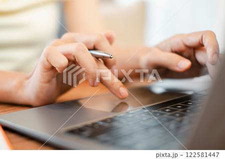 Hands typing on a laptop keyboard with a pen, representing digital work and communication. 122581447