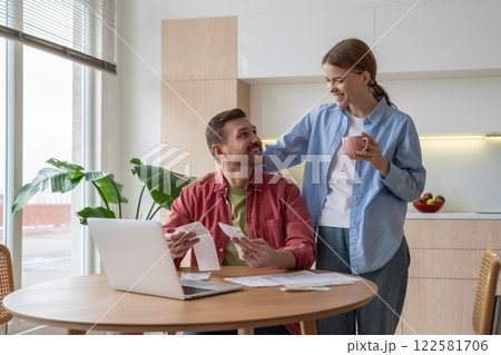 Pleased married couple pay bills count taxes using easy internet banking service on laptop at home. Pleased married couple pay bills count taxes using easy internet banking service on laptop at home. 122581706