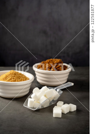 Different type of sugar, light brown, dark brown and white sugar cubes in bowls.  122581877