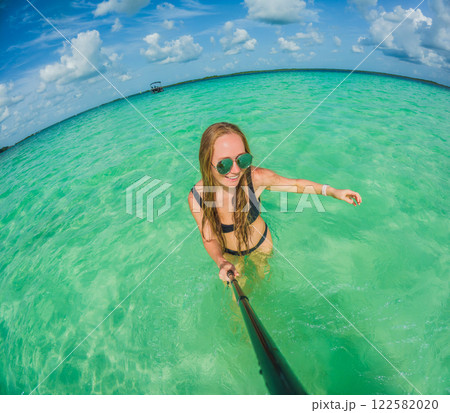 Woman standing in the crystal-clear waters of Lake Bacalar, Mexico, enjoying the serene beauty of the landscape. Tranquil moment in nature, outdoor escape, and relaxation concept Woman standing in the crystal-clear waters of Lake Bacalar, Mexico, enjoying the serene beauty of the landscape. Tranquil moment in nature, outdoor escape, and relaxation concept 122582020