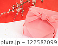 紅白の和紙に置いたピンクの風呂敷包みと桜の枝 122582099