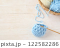 木目の机に置いた水色の編み物と毛糸とカゴ 122582286